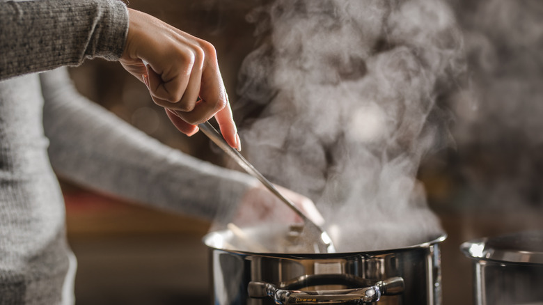 Hand stirs boiling pot