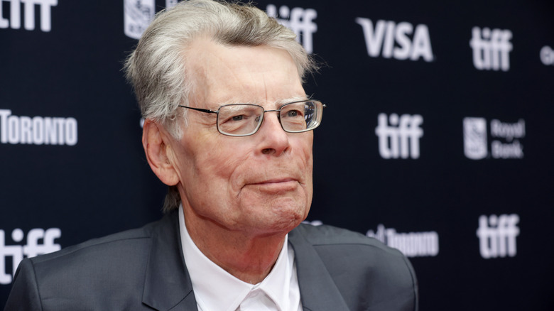 Stephen King smiles on a red carpet.
