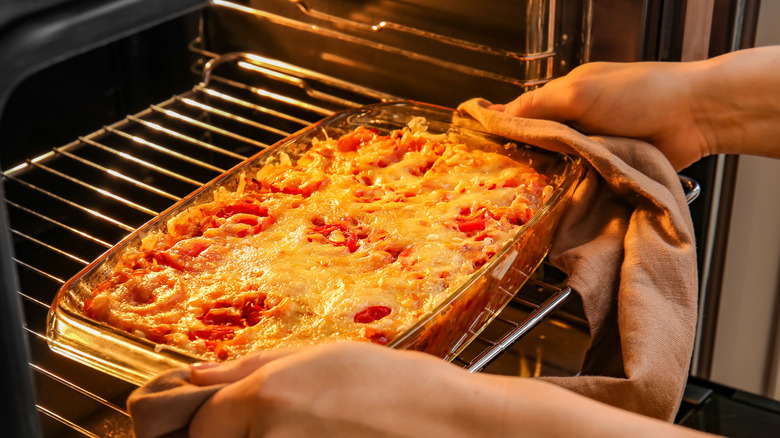 A cheesy baked rice dish being taken out of the oven