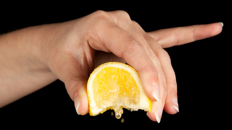 Hand squeezing lemon wedge