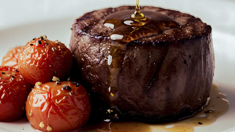 Closeup of a filet mignon with grilled tomatoes and oil