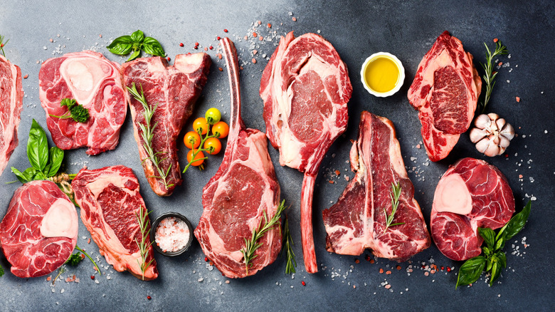 A variety of cuts of beef rest against a grey background