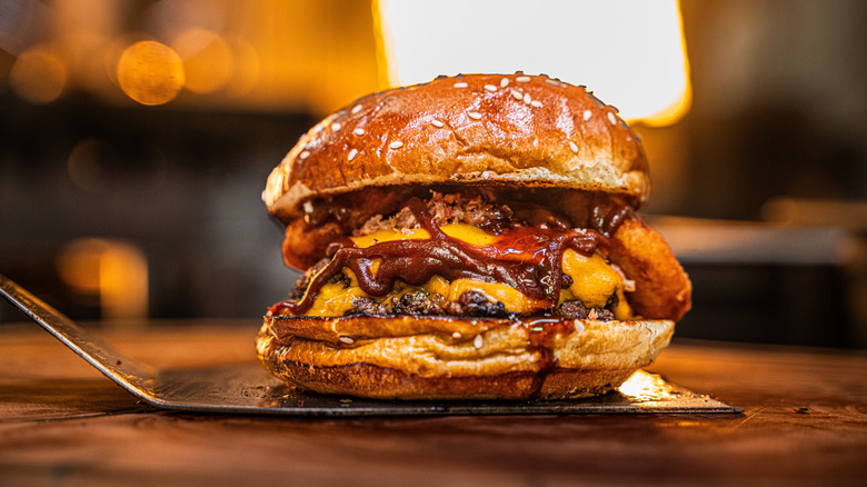 A cheeseburger sits on a spatula.