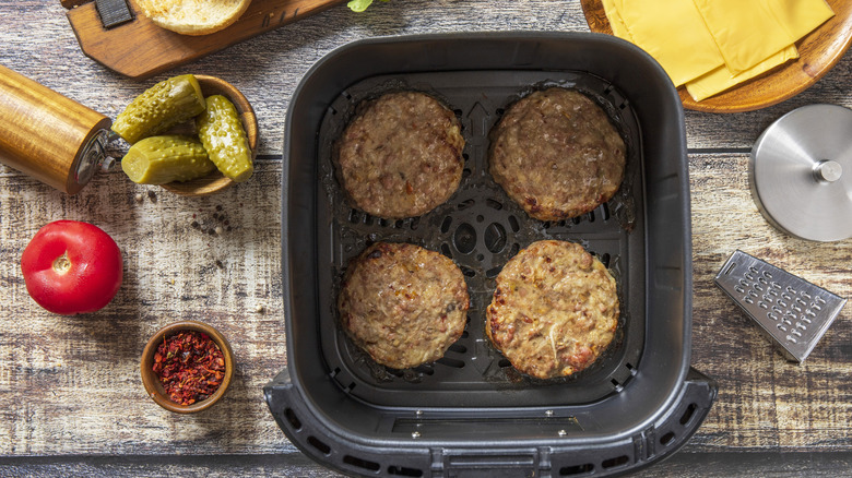 Burger patties heating inside of an air fryer.