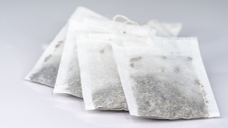 Four white teabags on a white surface