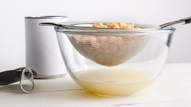 Can of chickpeas with beans in sieve draining in bowl