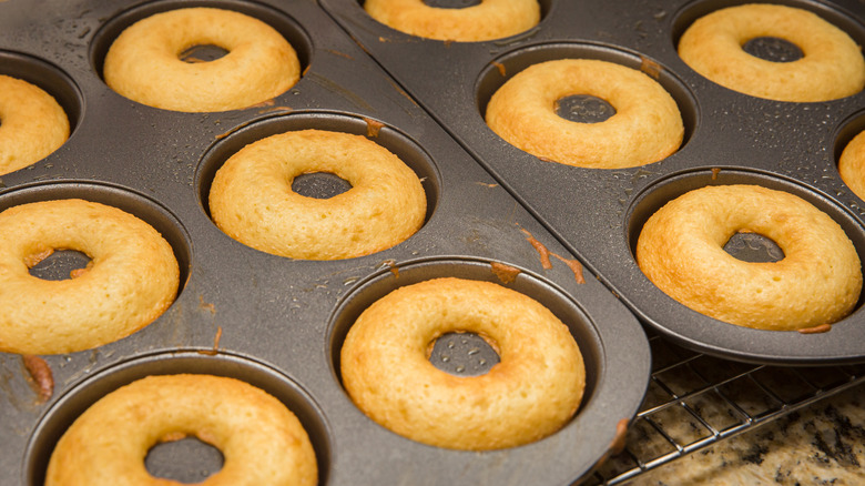 Two trays of baked donuts on a cooling rack