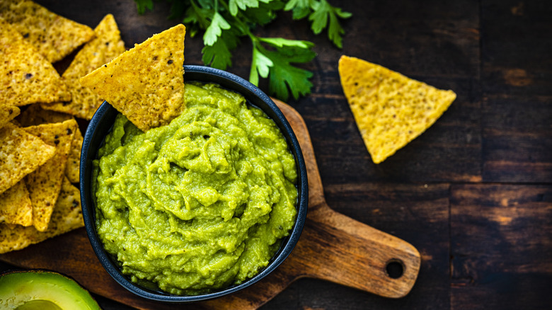 A bowl with guacamole with tortilla chips