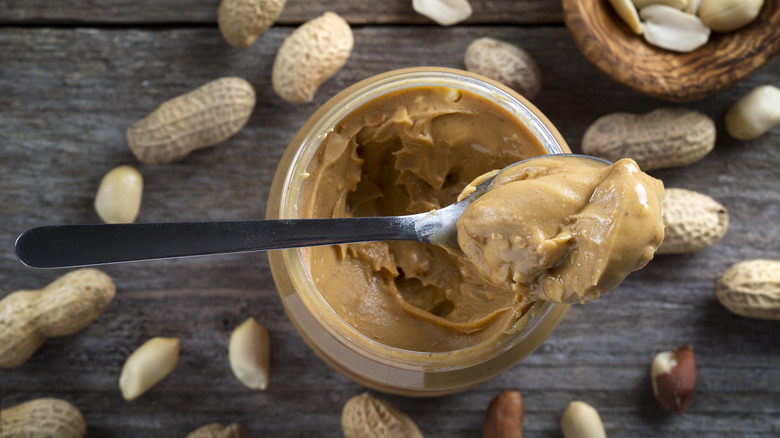 A spoon of peanut butter over a jar
