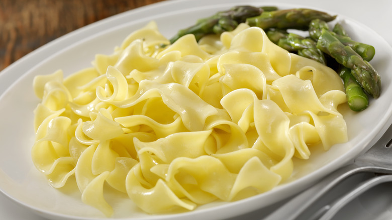 Plate of buttered egg noodles with asparagus on the side