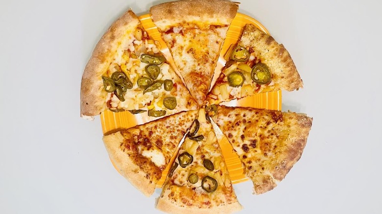 Six slices of plain and jalapeno pineapple stuffed crust pizza on orange plate