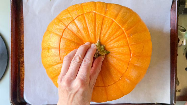 Pumpkin with carved lid on baking sheet