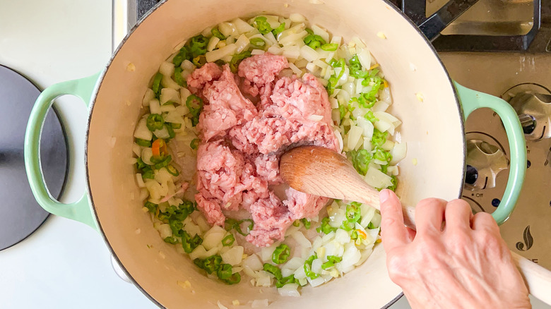 Ground pork in pot with vegetables on stove