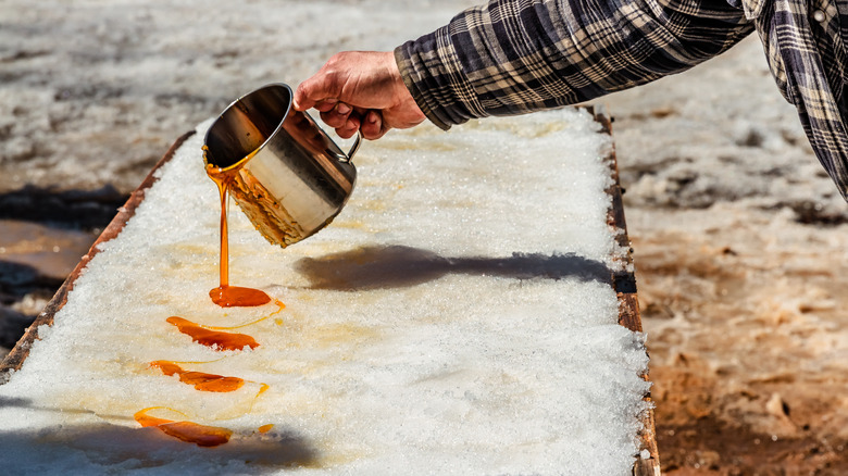 person pours hot maple syrup onto snow