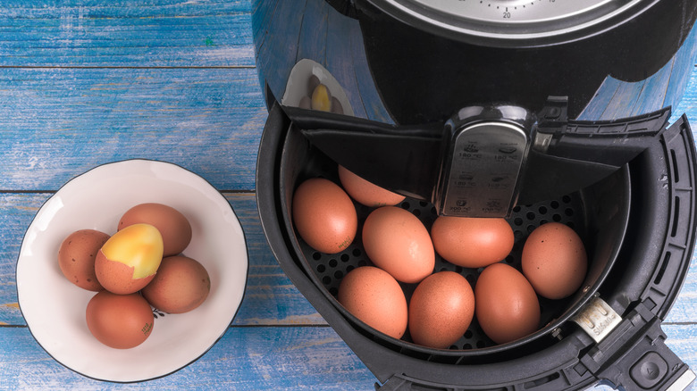 eggs in air fryer next to bowl of eggs