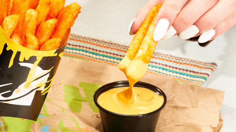 Person dipping Taco Bell vegan nacho fries