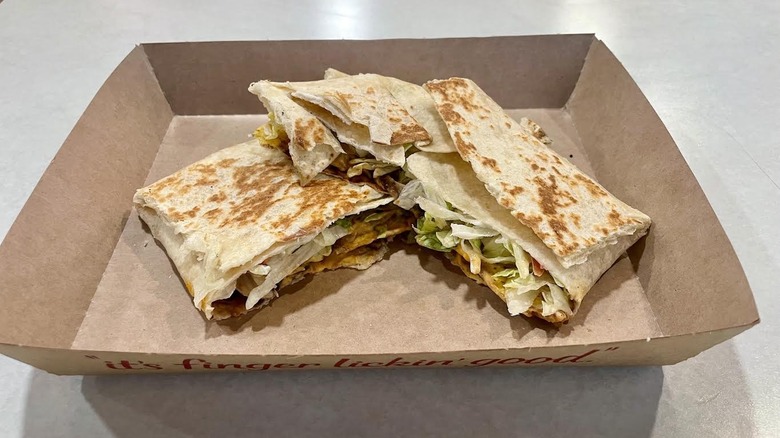 A cardboard serving dish with Taco Bell's Black Bean Crunchwrap Supreme
