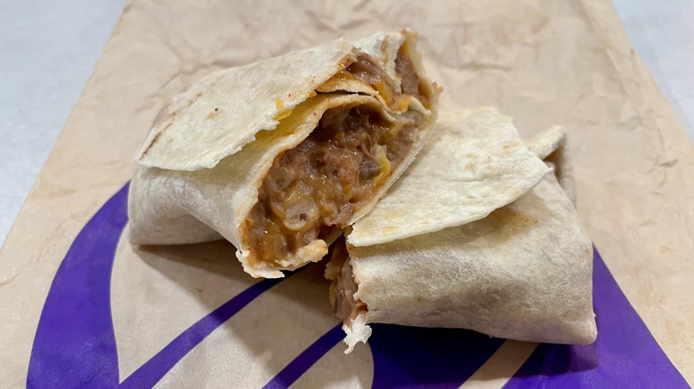 Two halves of a Taco Bell Bean Burrito on a white table top