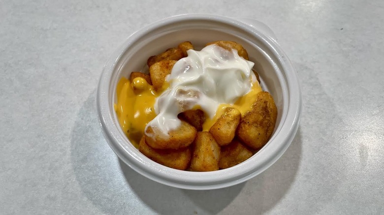 A small white dish of Taco Bell's Cheesy Fiesta Potatoes on a white table top