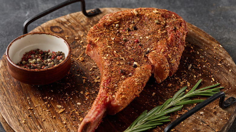 Dry rub steak seasoned with various spices on wooden serving platter