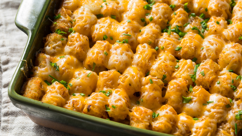 Tater tots in baking dish with melted cheese and chives