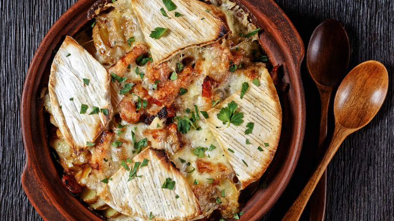 Tartiflette in a round baking on a dark wood surface 