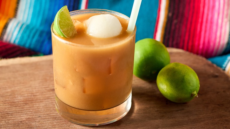 A glass of tejuino with two whole limes