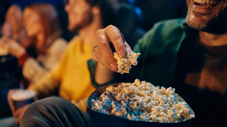 Person eating popcorn in movie theater.