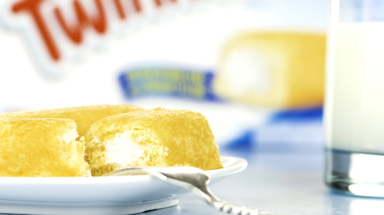 Twinkies cut in half on a plate with a box behind them.