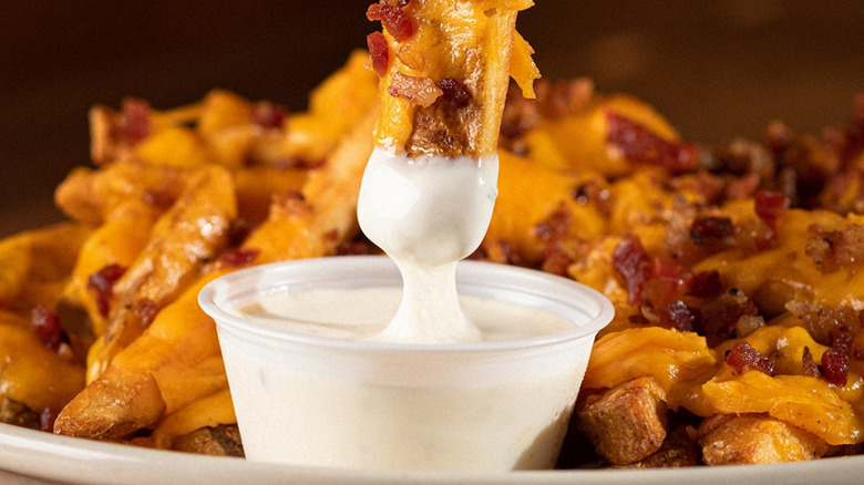 A diner dips loaded fries into Texas Roadhouse ranch dressing