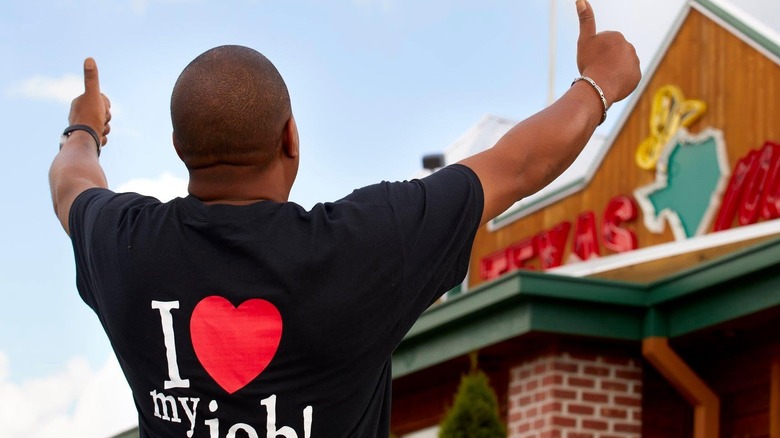 A Texas Roadhouse worker gives a double thumbs up outside a restaurant