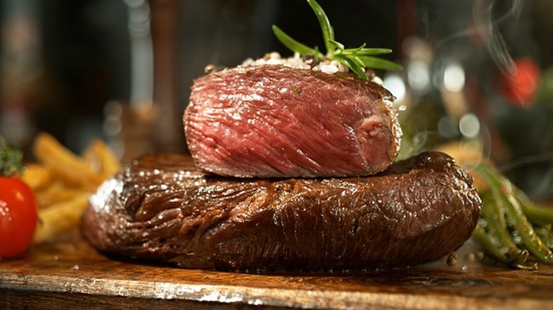 Hot steak on a board next to tomatoes and asparagus