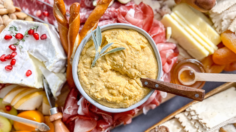 Pumpkin-sage hummus in bowl on charcuterie board