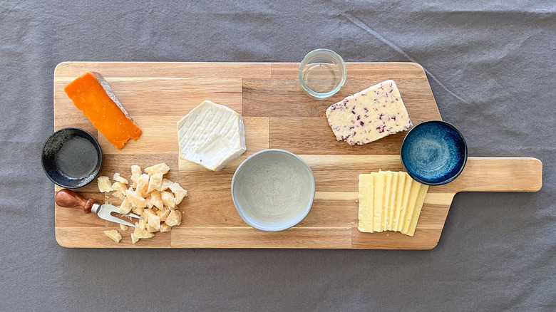 Assorted cheeses and serving bowls on board