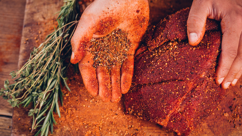 man seasoning a steak with spices