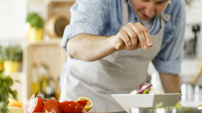 man seasoning salad