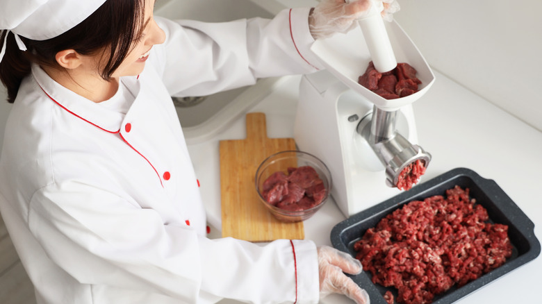 Chef grinding meat in a meat grinder