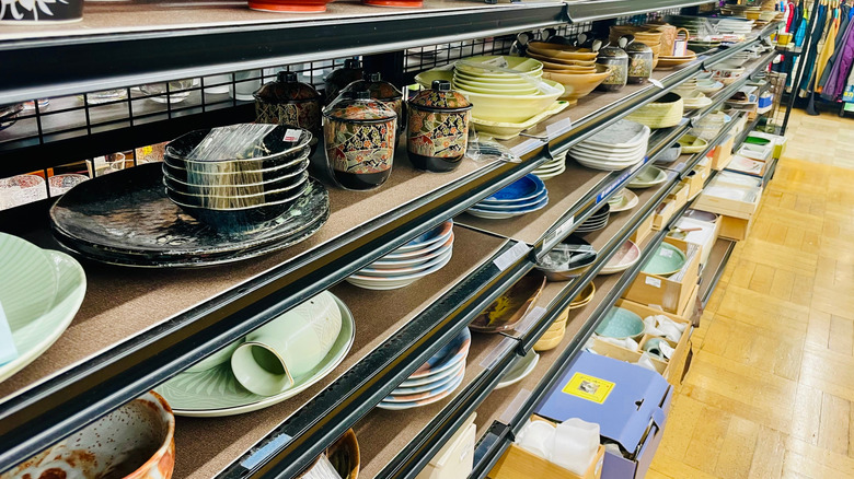 Racks of mismatched plates and other dishware on display in thrift store