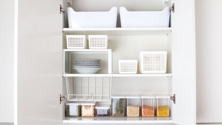 Plastic bins, baskets, and airtight containers in kitchen cabinet