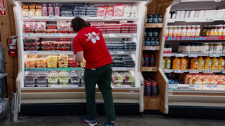Trader Joe's employee stocking produce cooler full of berries