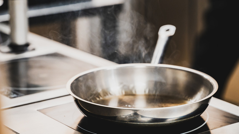 Closeup of a smoking stainless steel skillet on an induction hob