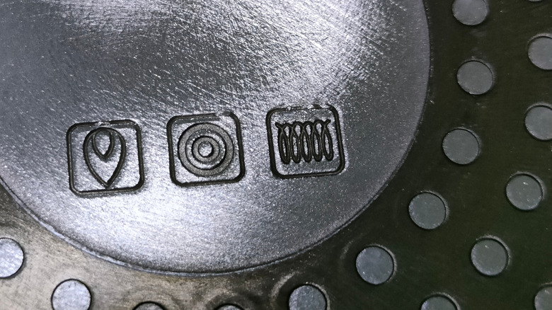 Closeup of symbols on cookware indicating stovetop compatibility