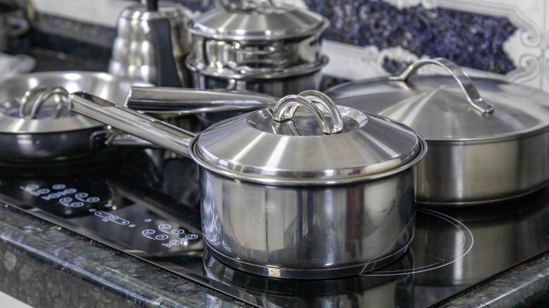 A set of stainless steel pans covers an induction hob
