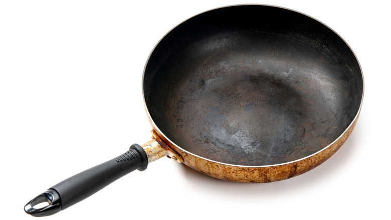 A rusted and warped skillet against a white background