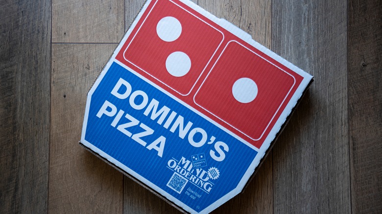 A Domino's pizza box on a wooden floor