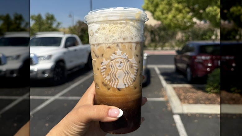 Hand holding Iced Brown Sugar Oatmilk Shaken Espresso