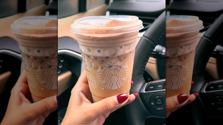 Hand holding Iced Peppermint White Chocolate Mocha inside of a car