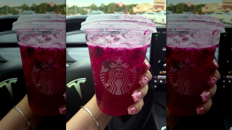 Hand holding a Starbucks Mango Dragonfruit Lemonade inside a car
