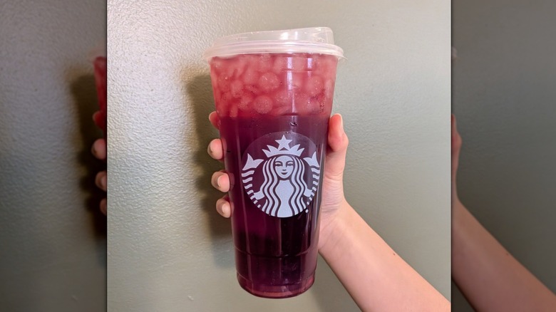 Hand holding Starbucks' Passion Tango Tea Lemonade