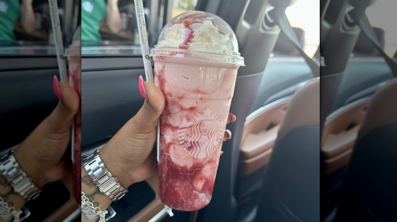 Hand holding Starbucks' Strawberries and Cream Frappuccino inside a car
